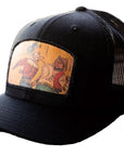 Black cap with a colorful patch featuring cartoon characters on a wooden surface.