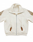 A person wearing a beige 'SLASHED FEATHER' blouson with leather feathers on the hood and sleeves, paired with blue jeans.