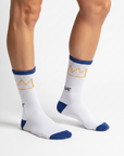 A pair of white crew socks with blue ribbed cuffs and heels, blue toes, and a yellow crown graphic above the word 'UIAT' printed in black.