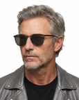 Grey-haired model wearing Kinney sunglasses and a matching grey leather jacket