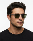 Dark-haired male model wearing Garrett Leight Brooks sunglasses with Light Light Grey frames and Pure G15 lenses on a white background