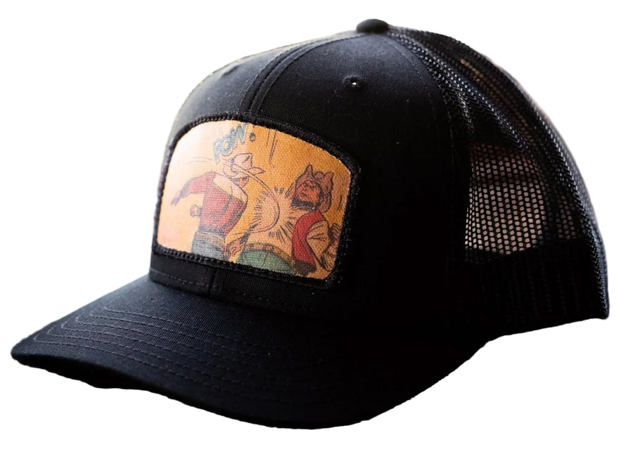 Black cap with a colorful patch featuring cartoon characters on a wooden surface.