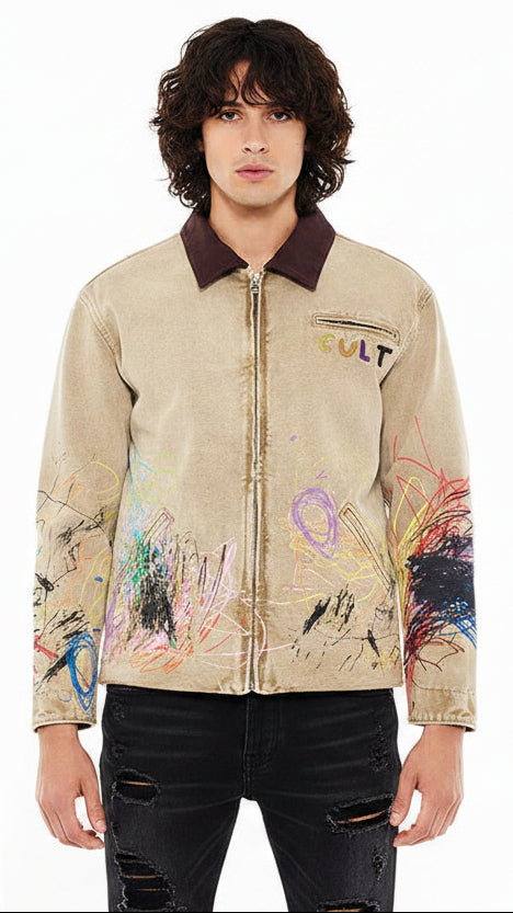 Male wearing a beige jacket with paint splatters in different colors one the lower half.  Brown collar.
