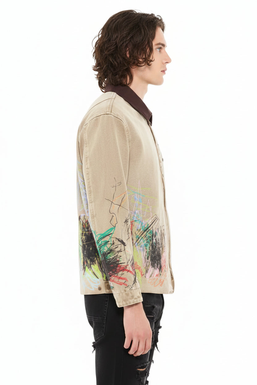 A man shown in profile wearing a light beige denim jacket with colorful abstract graffiti-style paint splatters on the lower front and sleeves, paired with white pants against a plain white background.