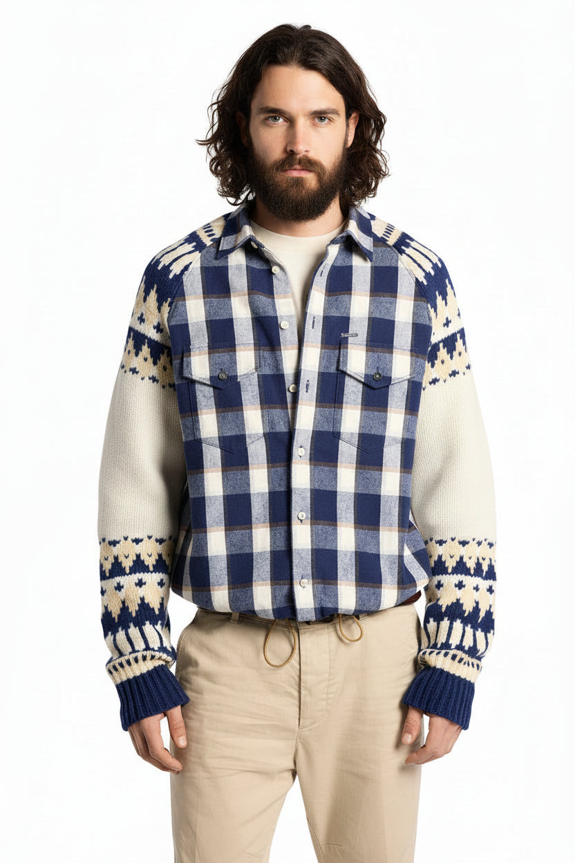 A male model wearing a blue and cream plaid button-up shirt layered over a cream knit sweater, paired with beige drawstring pants, against a plain white background.
