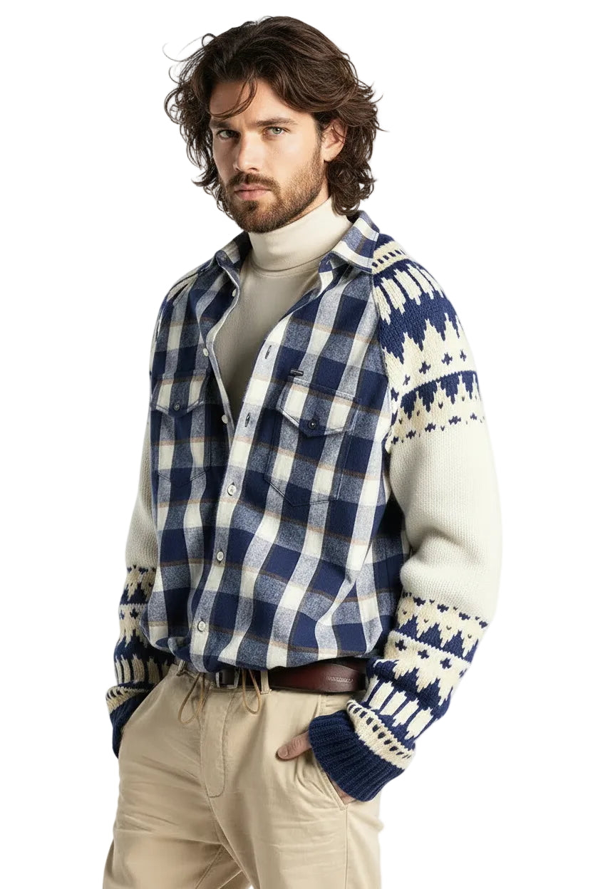 A young man wearing a blue and white plaid button-up shirt layered over a cream knit sweater with blue and cream Fair Isle patterned sleeves and cuffs, paired with beige pants and a brown belt, against a solid white background.