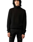 Male model with black hair and wearing a black turtleneck cashmere sweater and distressed black jeans