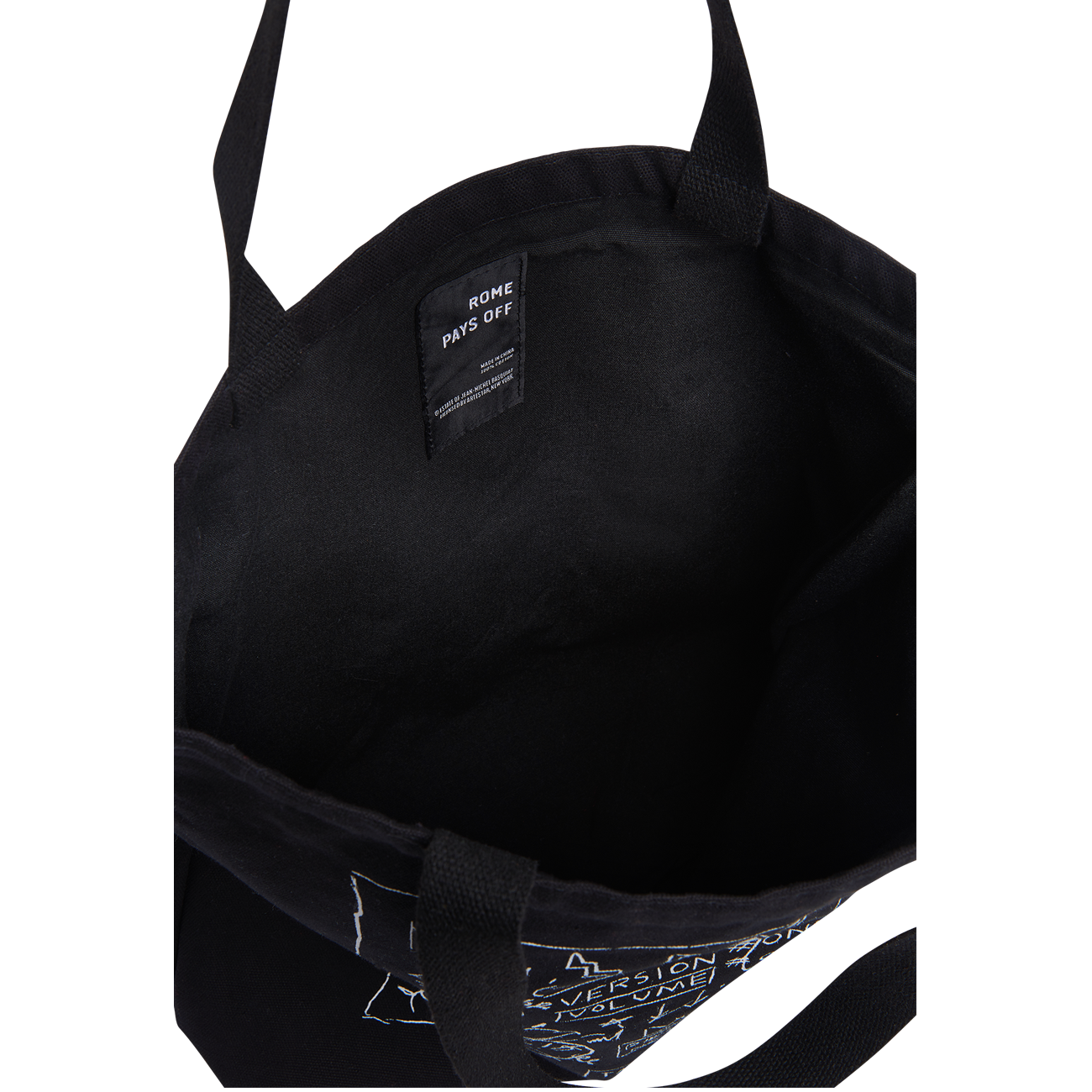 Black canvas tote bag shown from the inside, featuring black webbing handles and a black interior label that reads 'ROME PAYS OFF'.