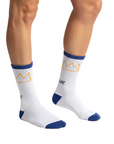 Model wearing Rome Pays Off Basquiat "Crown" crew socks in white with gold crown motifs and blue cuffs, heels, and toes.