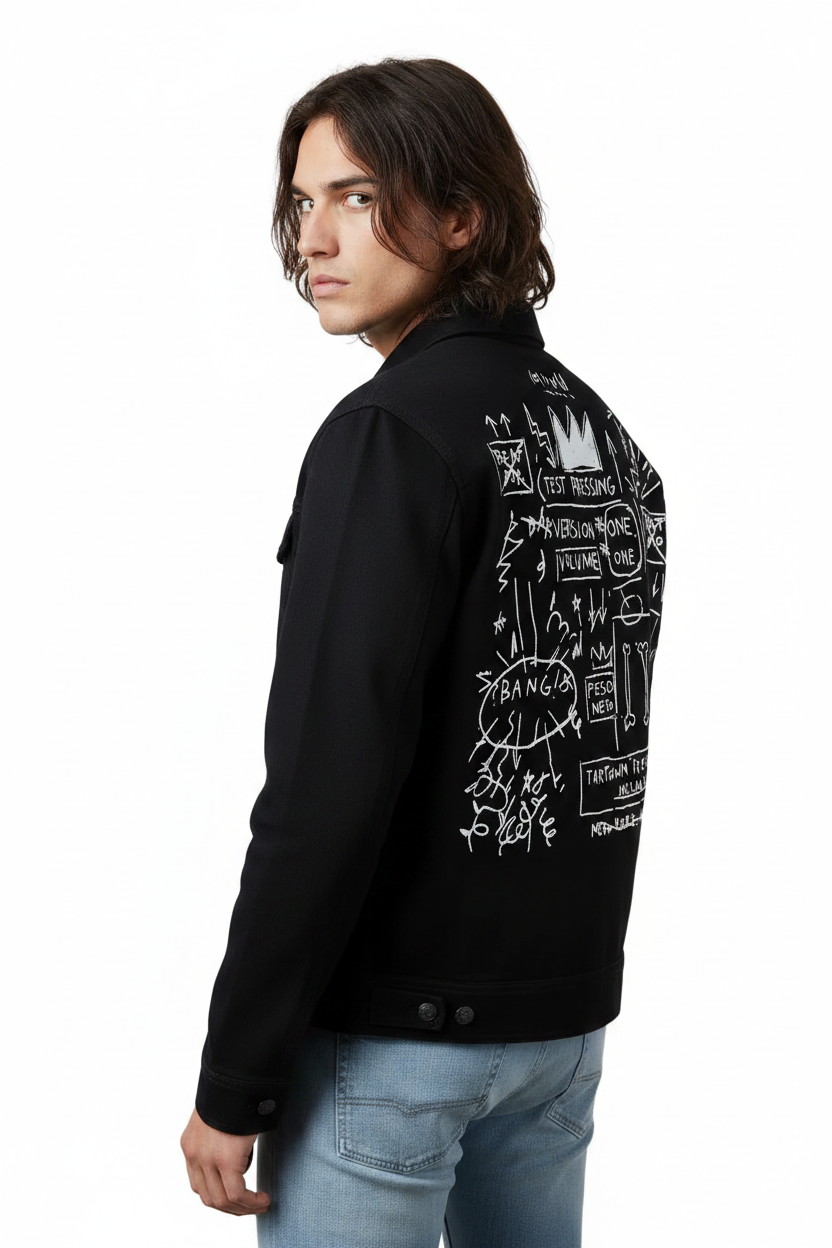 Person wearing a black jacket with white graphics on the back, standing indoors.