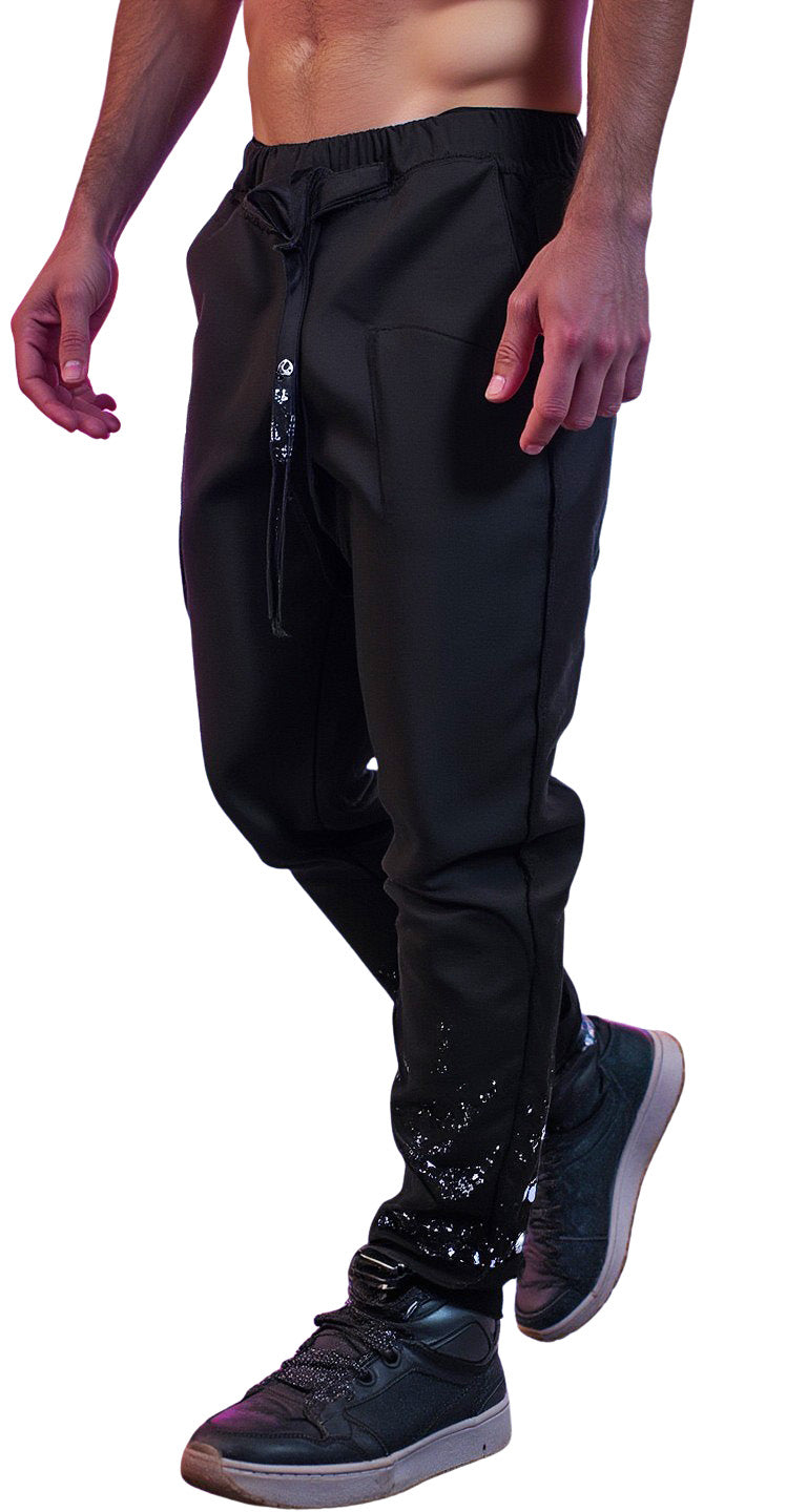 ZHANNAONA "Drip" black linen pants on model, showing adjustable belt, exposed side seams and paint-splashed lower legs.