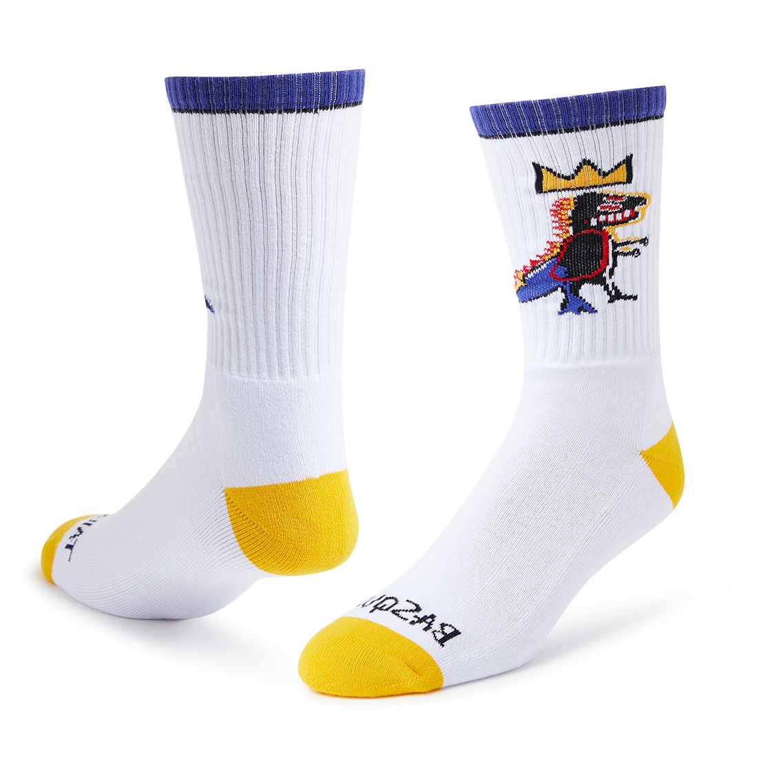 A pair of white crew socks with yellow toes and heels, purple cuffs, and a colorful cartoon graphic on the upper right sock. The brand name 'BROOKS' is printed in black on the sole of the front sock.