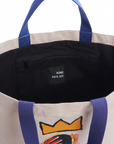 Interior of the Rome Pays Off Basquiat tote showing dark lining, zippered pocket and blue straps